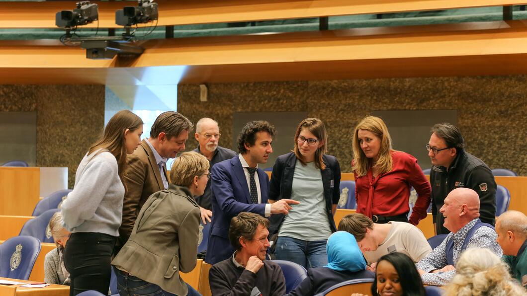 Jesse Klaver in de Tweede Kamer omringd door een groep mensen die aan zijn lippen hangt